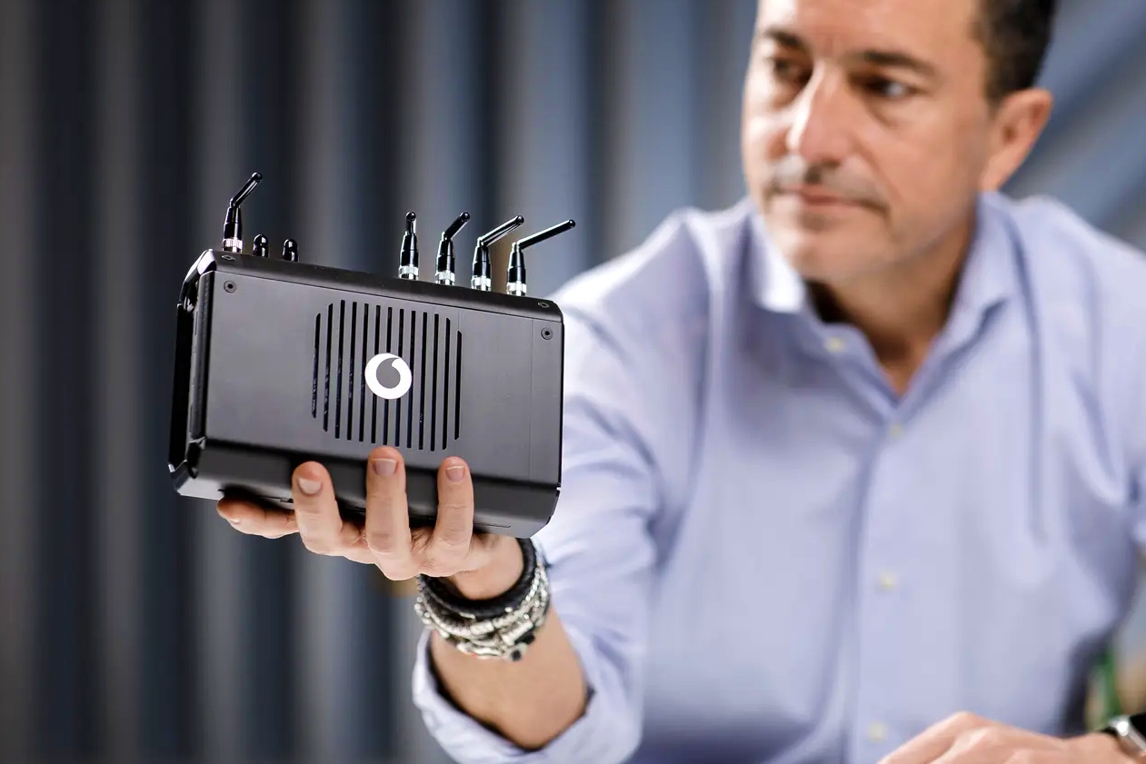 photo of a man holding a miniature 5G base station built around a modified Raspberry Pi mini desktop PC