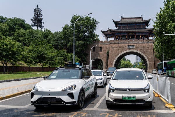 Two white cars on a road in China with other cars behind them.