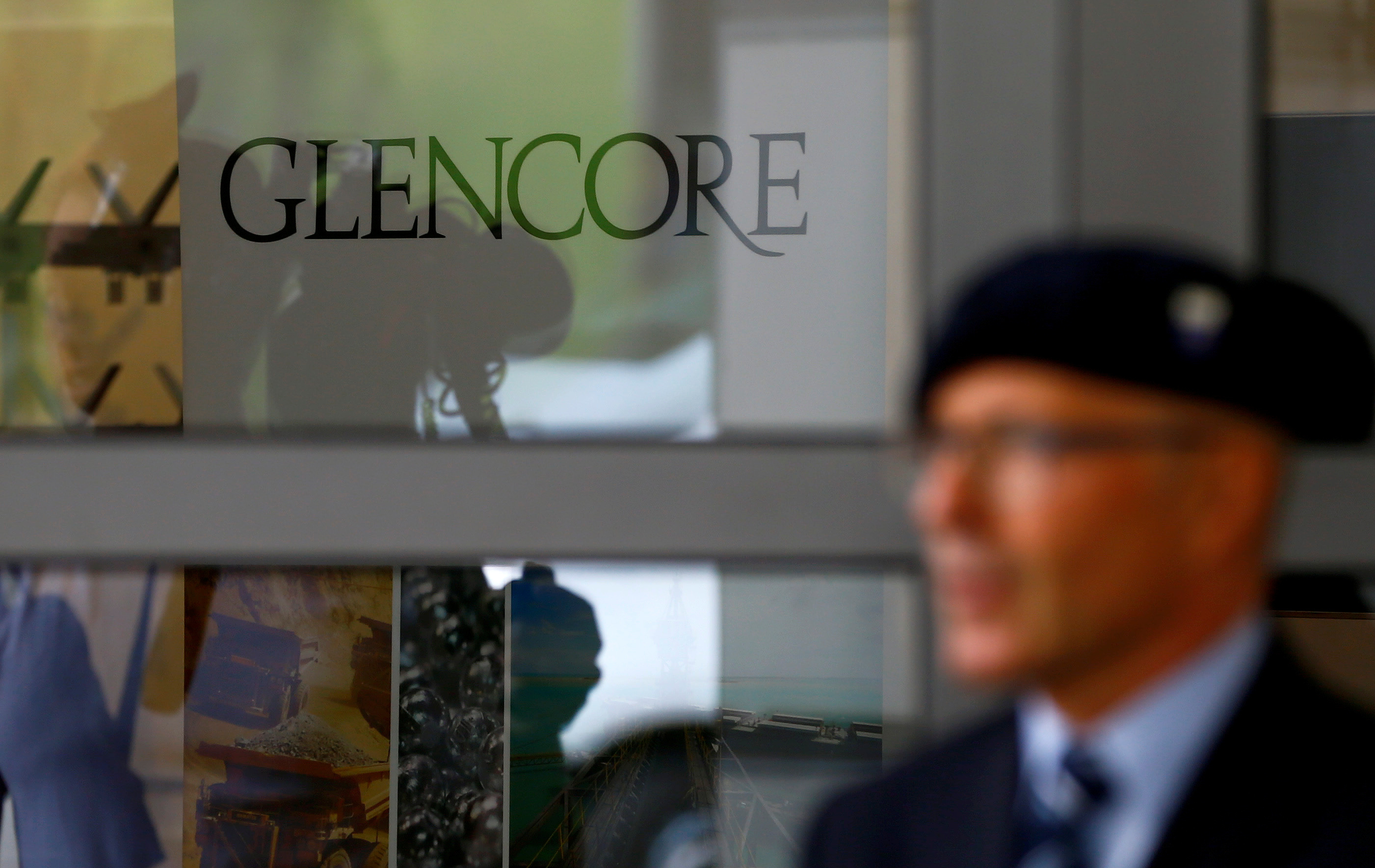 An employee of a private security company stands in front of the logo of commodities trader Glencore in Cham
