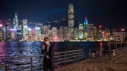 FILE - A man talks on his phone in front of the skyline in Hong Kong, Oct. 19, 2022.